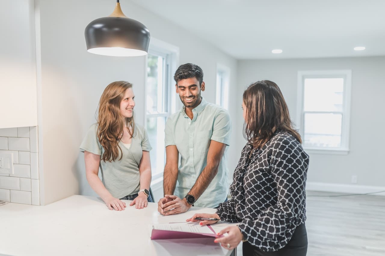 Three people standing around a table talking to each other.