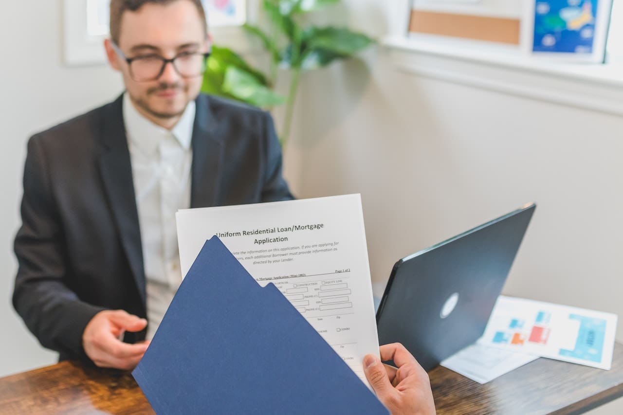 A man is holding papers while sitting at a table.