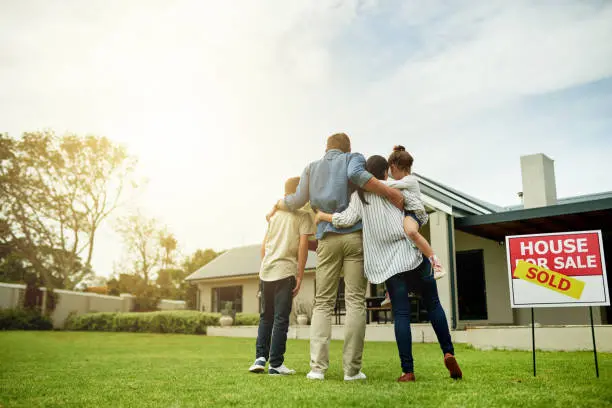 A group of people standing in the grass near a house.