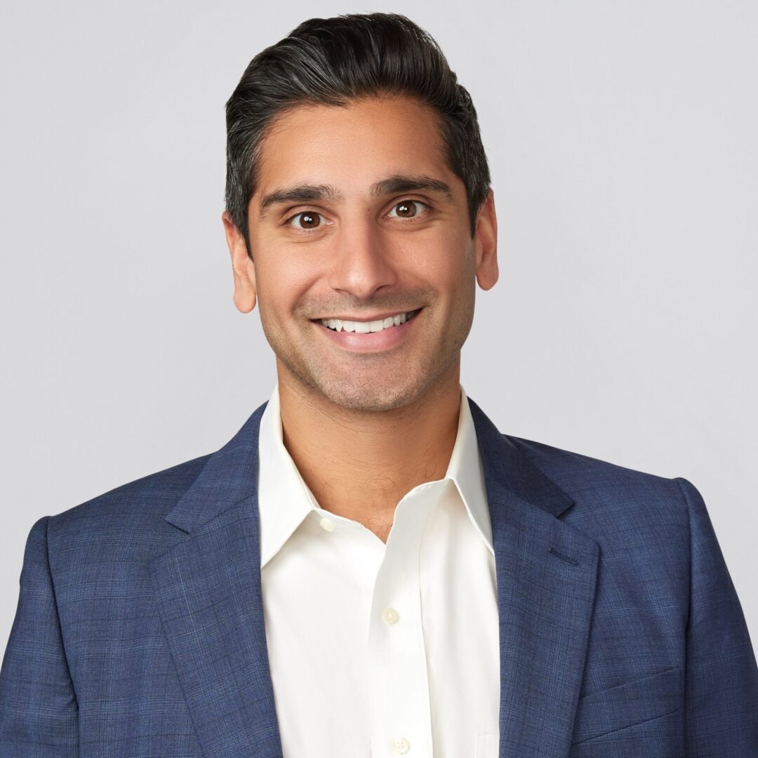 A man in a suit and tie smiling for the camera.